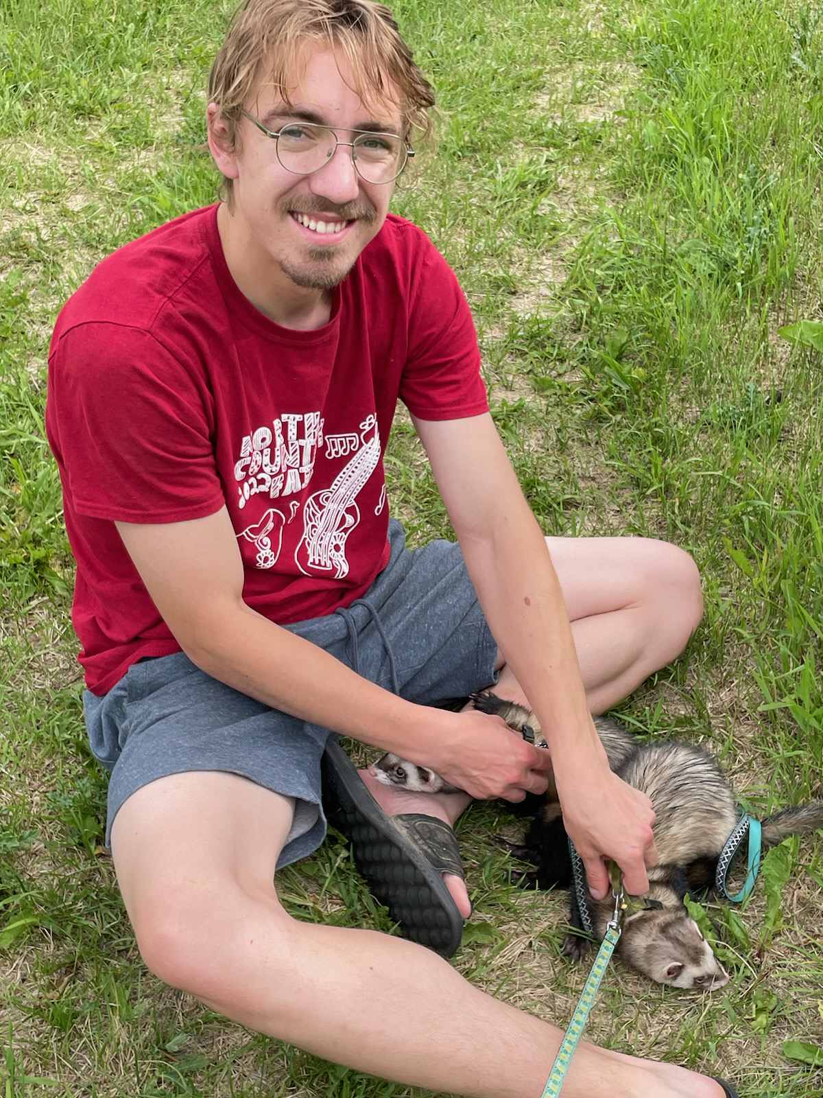 A man with cystic fibrosis sites cross-legged in the grass.