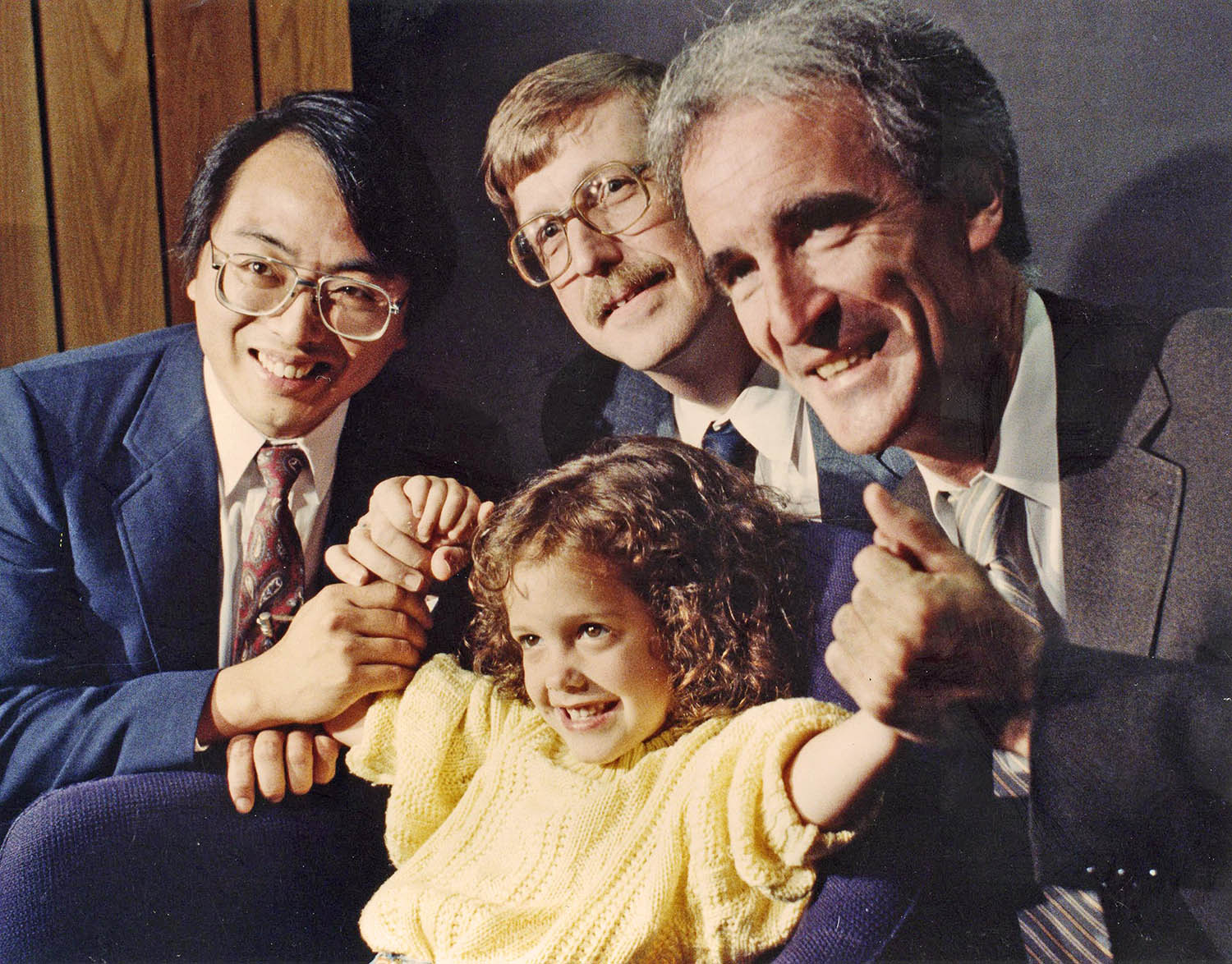 A photo from 1989 of a young girl with cystic fibrosis posing with scientists from this era.