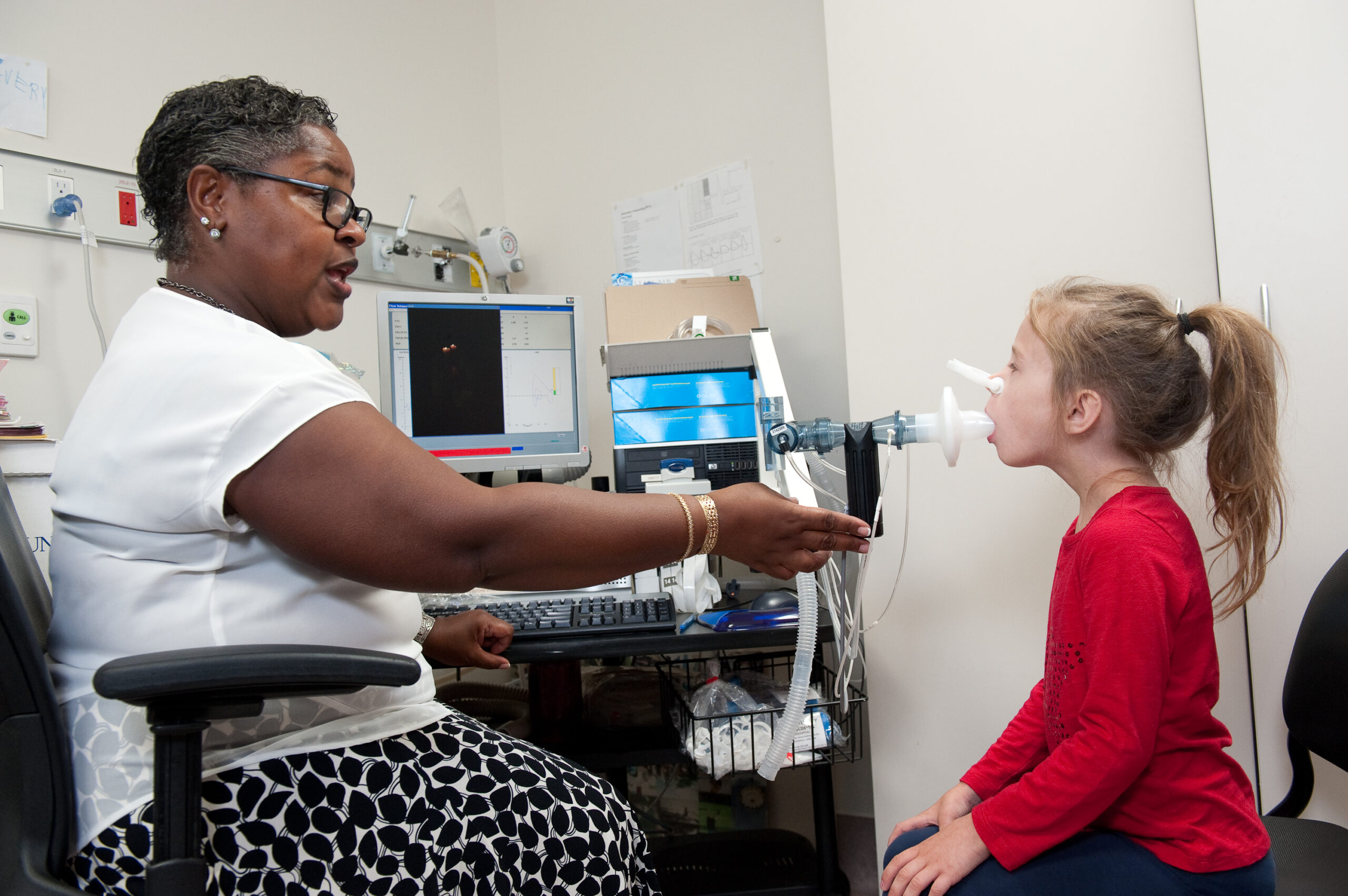 A female CF doctor performs a lung capacity test on her young patient.