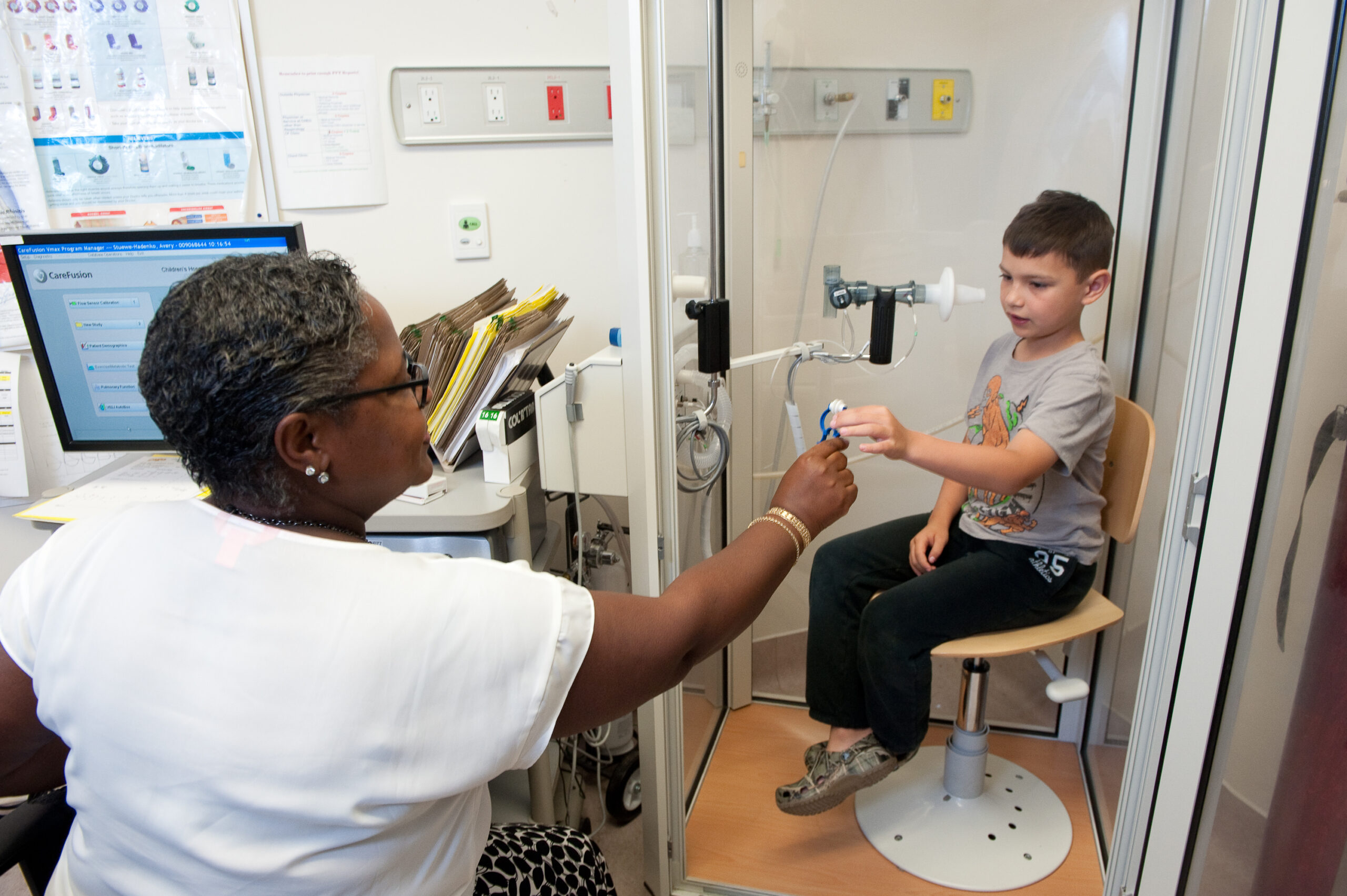 A young boy performs a lung test with the help of a female medicalprofessional.